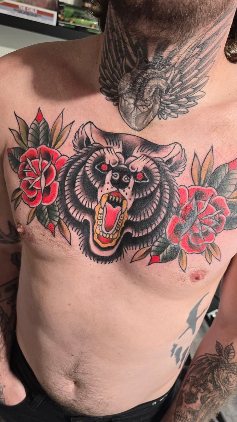 Traditional bear head between two roses, across the chest