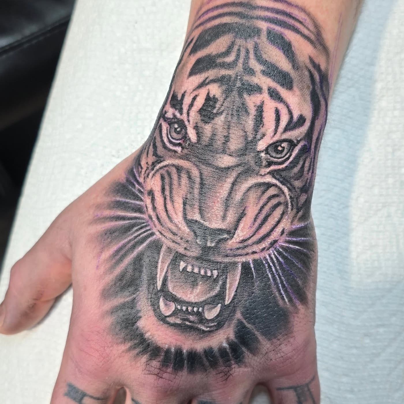 Snarling tiger head covering the back of a hand