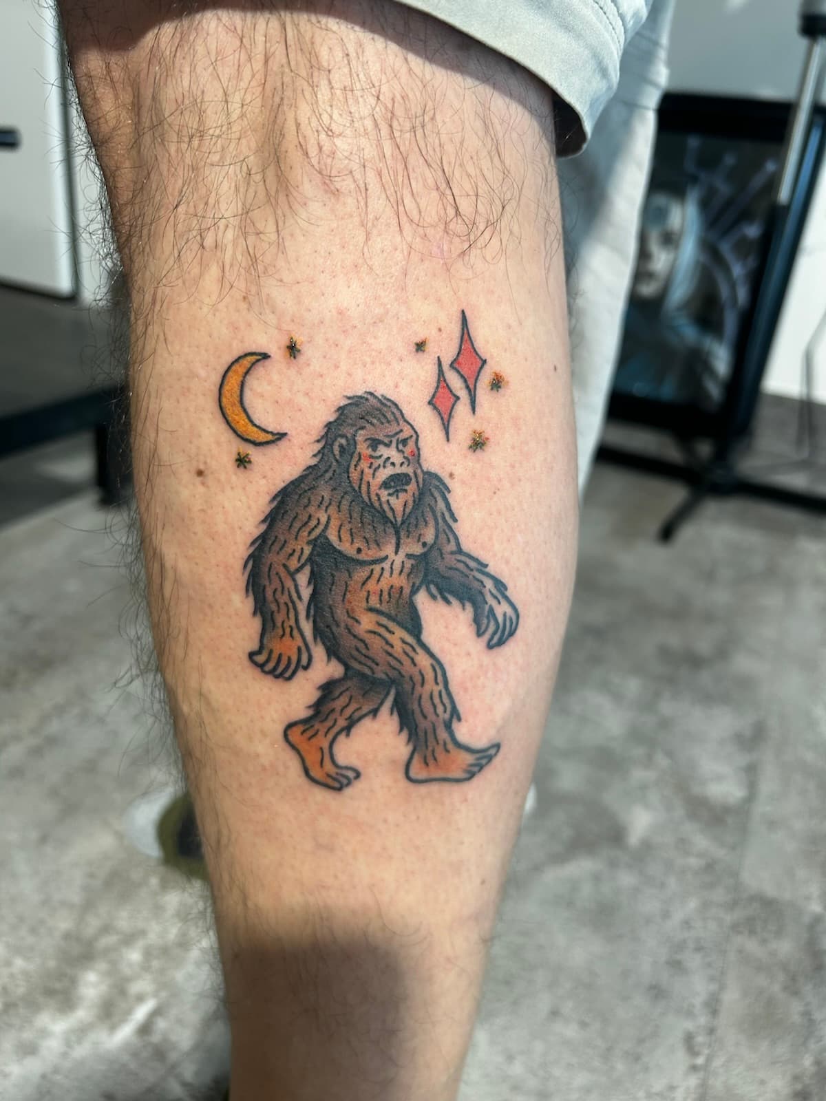 Bigfoot walking under a crescent moon and red stars, colour on the calf