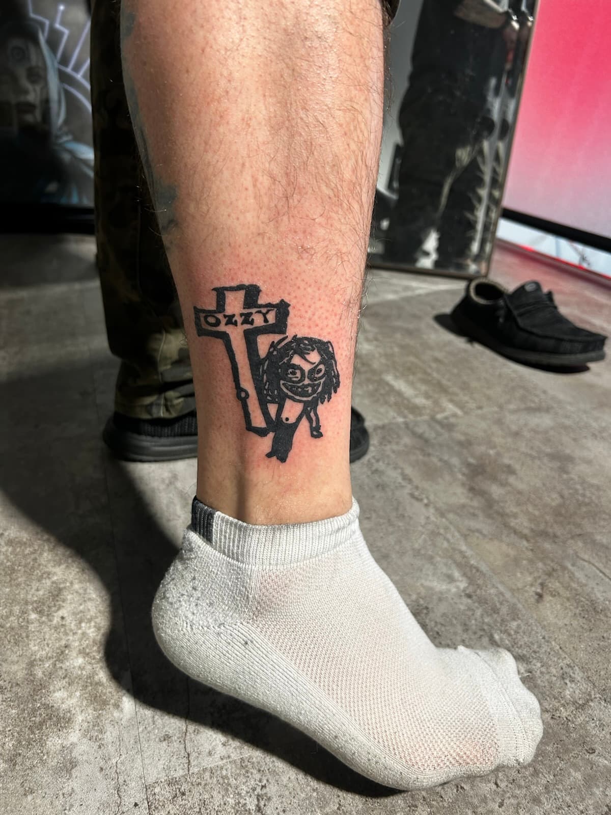 Cartoon Ozzy beside a cross reading 'Ozzy', solid black on the ankle