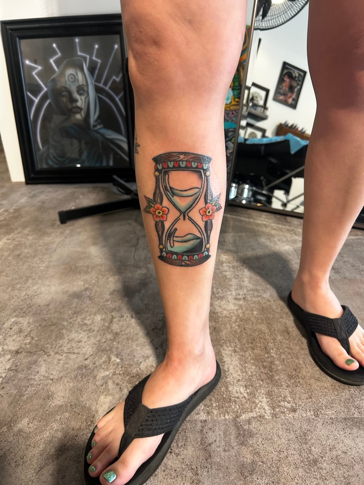 Wooden hourglass with blue sand and two red flowers, colour on the calf