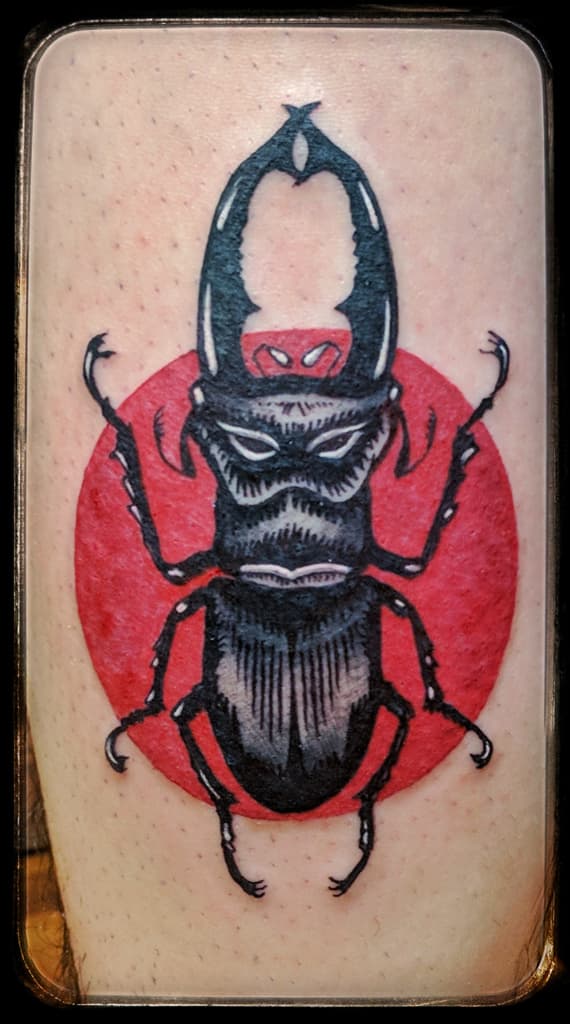 Stag beetle over a solid red circle, black and grey with red on the lower leg