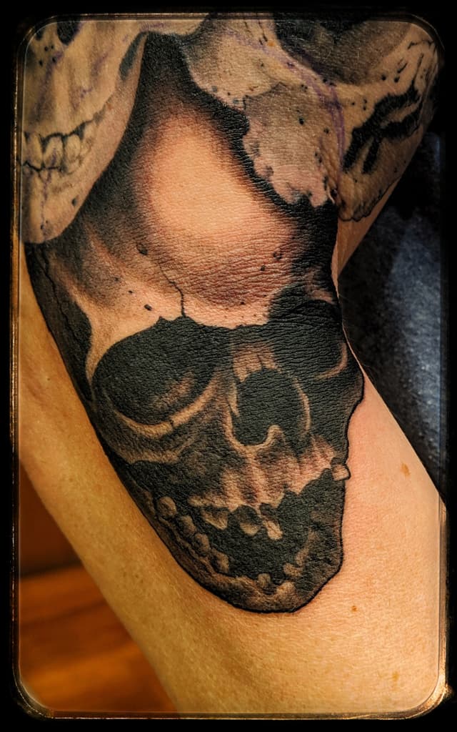 Skull shaded in heavy black and grey across a bent joint, part of a larger skull piece