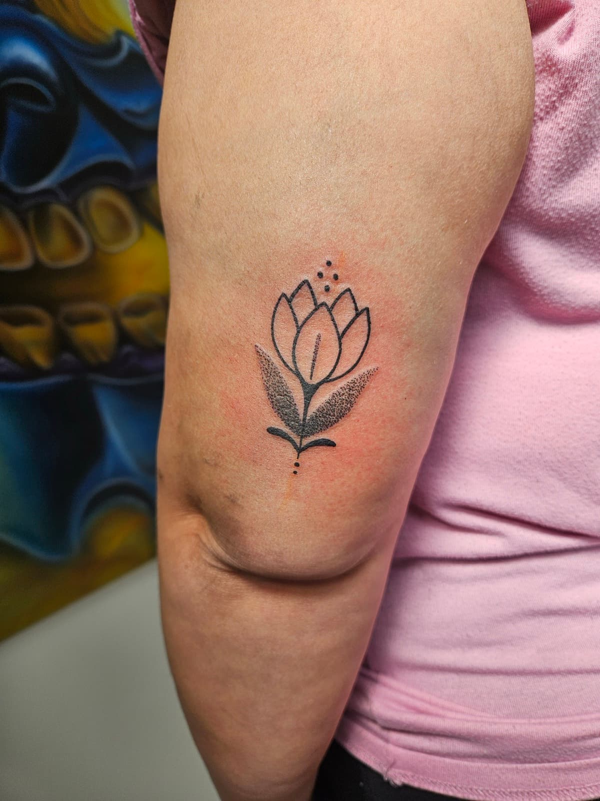 Tulip outline over two dotwork leaves, small fine-line piece on the back of the arm
