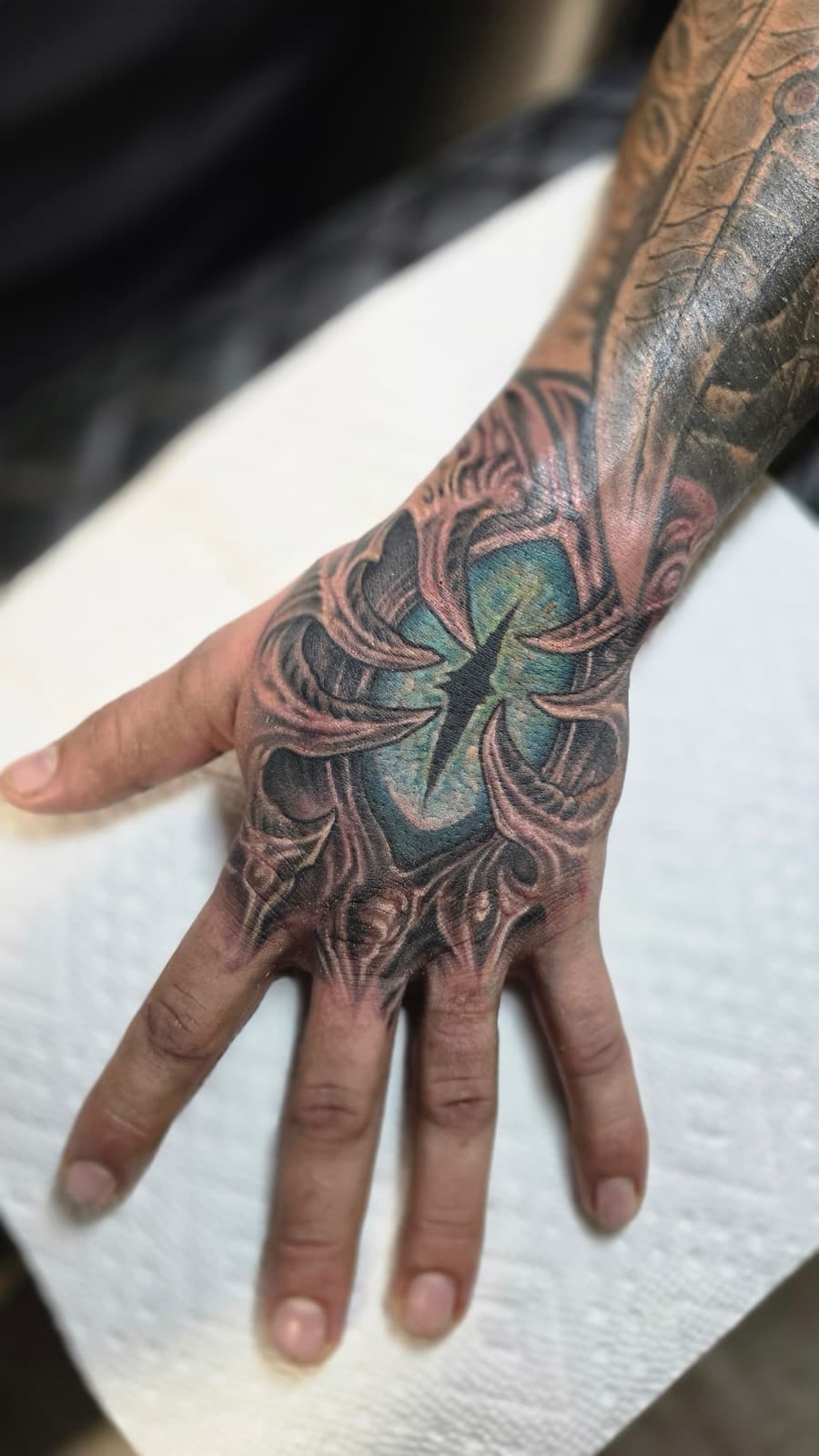 Glowing green eye with a slit pupil set in biomechanical bone on the back of the hand