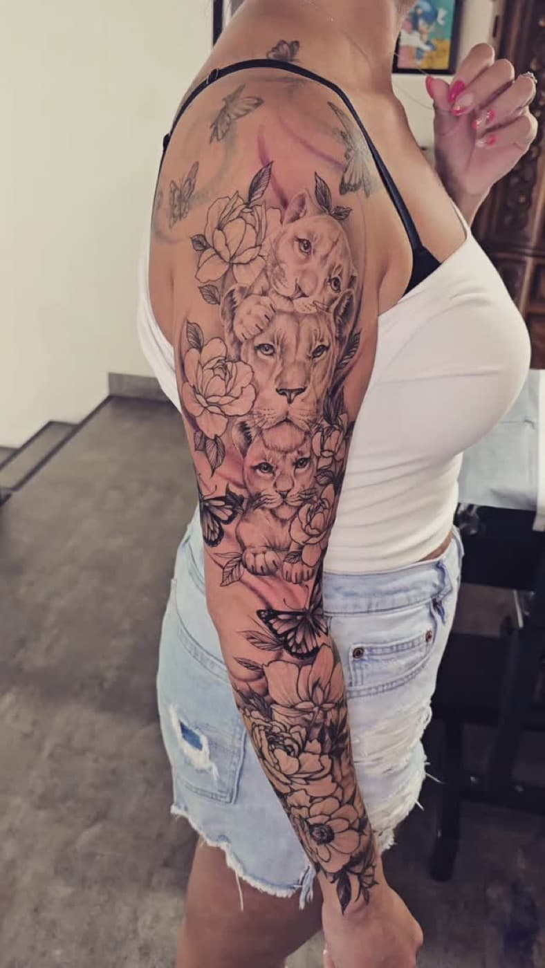 Lioness and two cubs among magnolias and butterflies, black and grey sleeve from shoulder to wrist